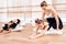 The trainer of the ballet school helps young ballerinas perform different choreographic exercises.