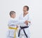 The trainer with black belt teaches karateka boy with yellow belt to beat the blow