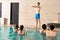 Trainer exercising water aerobics with young
