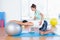 Trainer helping man with exercise ball