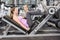 Trainer motivating pregnant woman while using leg press