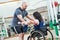 Trainer with woman in wheelchair lifting weight in gym. sport activity of people with disability