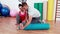 Trainer working with woman on exercise mat