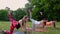 Training for perfect hips. Group of athletic young women in sportswear doing physical exercises with coach in green