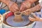 Training pottery, hands of a child and a master on clay, close-up