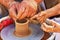 Training pottery, hands of a child and a master on clay, close-up