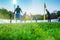 Training soccer players on football stadium. Green grass at foreground. Defocused.