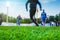 Training soccer players on football stadium. Green grass at foreground. Defocused.