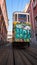 Tram with graffiti in narrow steep street in Lisbon