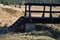 Tramping and hiking through uninhabited wild landscape on a footpath trampled in peat soil through dry autumn grass. wooden pedest