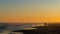 Tranquil beach scene at sunset with waves, clear sky and a few people