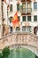 Tranquil canal with a bridge and venetian flag in Venice