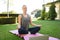 Tranquil caucasian woman practicing yoga in sunny garden, sitting and meditating with eyes closed