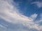 Tranquil cloudscape and the tiny moon on the blue sky. Fluffy white clouds aerial composition. Misty overcast cumulus shapes,