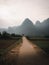 Tranquil country scene showcasing a dirt path surrounded by lush green hills and fields