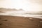 Tranquil display of the waves of a misty beach hitting the black sand and small stones