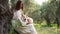 A tranquil embrace in nature: a woman cradles a corgi in a serene olive grove