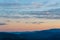 Tranquil evening landscape with blue mountains and pastel sunset colors and cirrus clouds