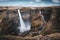 Tranquil Haifoss waterfall cascades into a deep river located in a mountainous landscape