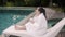 Tranquil lady in bathrobe with mug sits on couch near pool