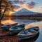 Tranquil lake scene at sunset with rowboats moored along shore with majestic silhouette snowy volcano in background. serene