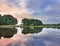 Tranquil landscape with a canal, trees, multicolored sky and dramatic clouds, Tilburg, Netherlands