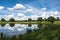 Tranquil landscape featuring a serene reflective pond surrounded by lush trees in a peaceful field