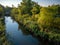 Tranquil landscape of a riverbank featuring a slow, steady flow of water surrounded by vegetation