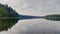 Tranquil meditative misty scenery of glacial lake with pointy fir tops reflection at early morning