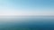 Tranquil minimalist landscape with a smooth blue sea surface with calm waters with a horizon and clear skies.