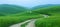 Tranquil misty rolling hills with lush greenery and winding path in serene landscape