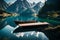 A tranquil mountain lake with a solitary boat moored at a rustic wooden dock, framed by majestic peaks and their reflections on