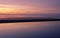 Tranquil pink and golden colored seascape at twilight over the abstract horizontal layers of mudflat at low tide