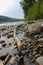 Tranquil river running through a wooded area, with calm waters and boulders dotting the landscape