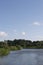 Tranquil river in summer: reedbeds, blue skies and water, windmill, house and holiday boat Norfolk Broads, UK