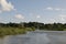 Tranquil river in summer: reedbeds, blue skies and water, windmill, house and holiday boat Norfolk Broads, UK