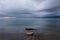 Tranquil rocky lake with clear water under dark clouds