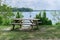 Tranquil scene of wooden table with two benches at the lake coast