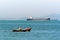 Tranquil Scenery of Fisherman on Small Boat with Large Nautical Vessel in Distant