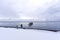 Tranquil sea with broken pier posts leading into the water, snow