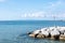 Tranquil seascape featuring several large rocks at the shoreline, with a flagpole