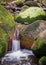 Tranquil Small waterfall flowing through mossy rocks in the riverbed