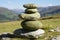 Tranquil stone stacks in green grass field with bright blue sky, serene nature landscape