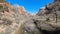 Tranquil stream flowing through a canyon with towering, sandy-colored mountains in the background