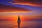 Tranquil Twilight: Sunset Cascading Over an Undulating Ocean, Distant Silhouette of a Solitary Sailboat on the Horizon