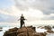 Trans sexual black person poses on scenic ocean beach like a goddess. Lgbtq ethnic fashion model in long posh dress and