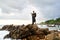 Trans sexual black person poses on scenic ocean beach like a goddess. Lgbtq ethnic fashion model in long posh dress and