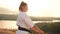 Translation: Kyokushinkai. Young woman white kimono demonstrates karate technique against backdrop nature