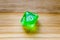 A translucent green ten sided playing dice on a wooden background with number zero on a top