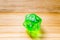 A translucent green twenty sided playing dice on a wooden background with number eighteen on a top
